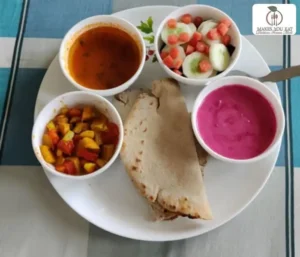 A good Indian thali with millet roti, sabji, salad, dal, and beetroot raita.