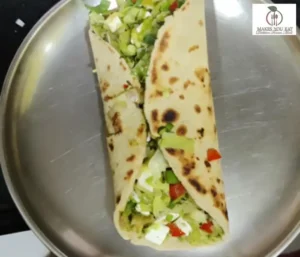 A steel plate showing High-protein paneer wrap with fresh lettuce and vegetables, a gut-friendly and filling meal option by Dt. Foram Modi.