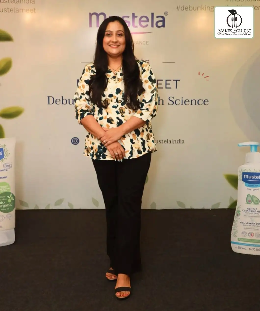 Dt. Foram Modi standing on stage at a corporate event in Mumbai.