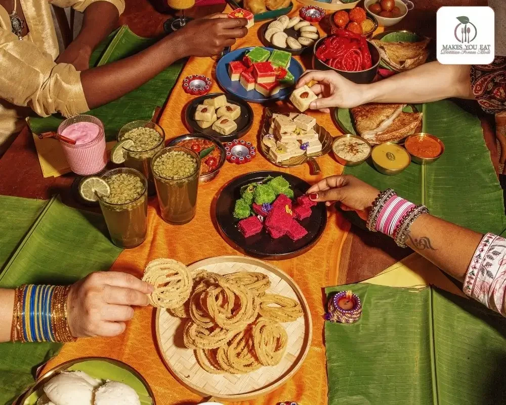 A Table full of Diwali Sweets with people hands taking sweets from bowls.