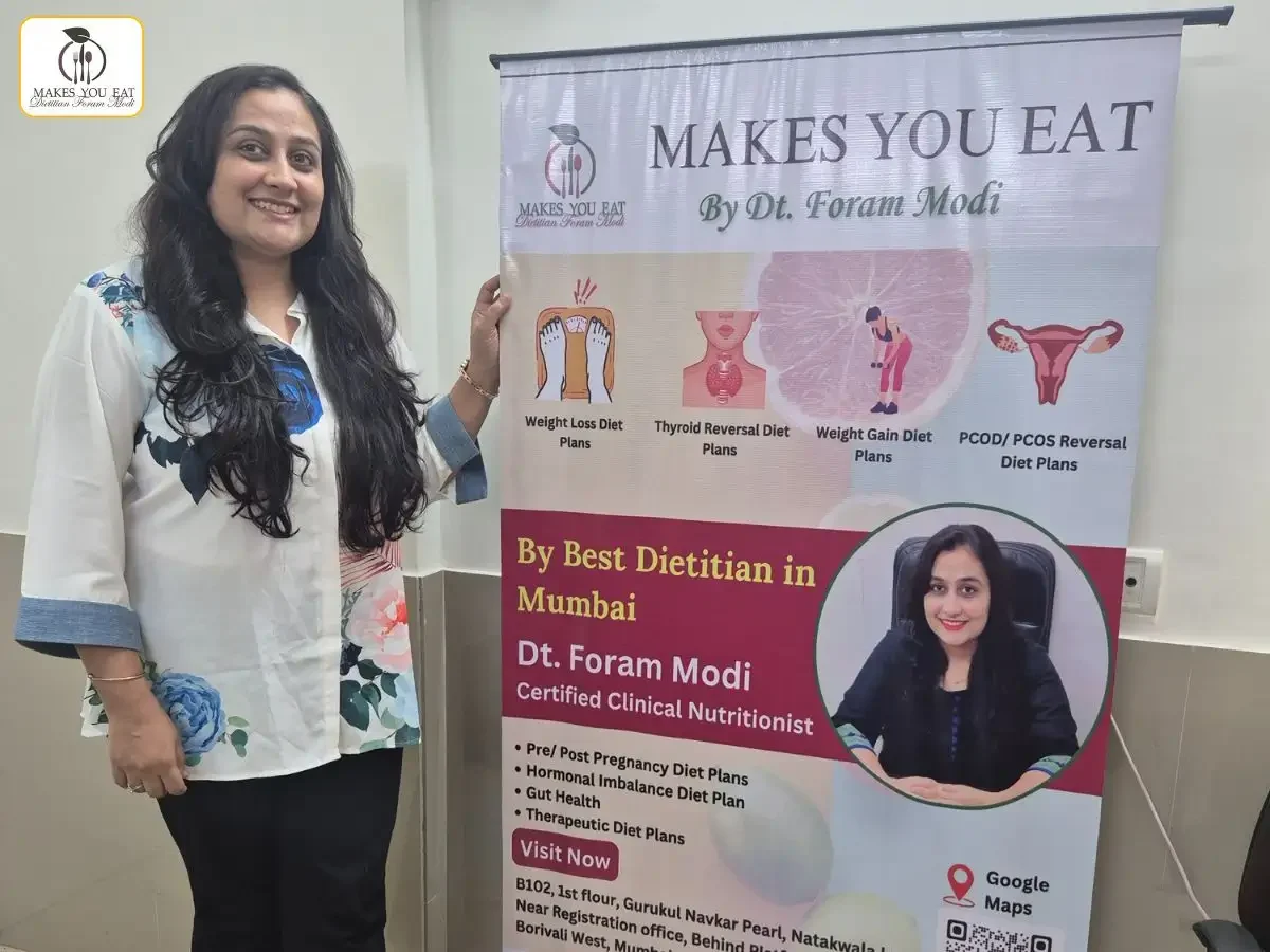 Dt. Foram Modi standing beside her marketing standee at her diet clinic.
